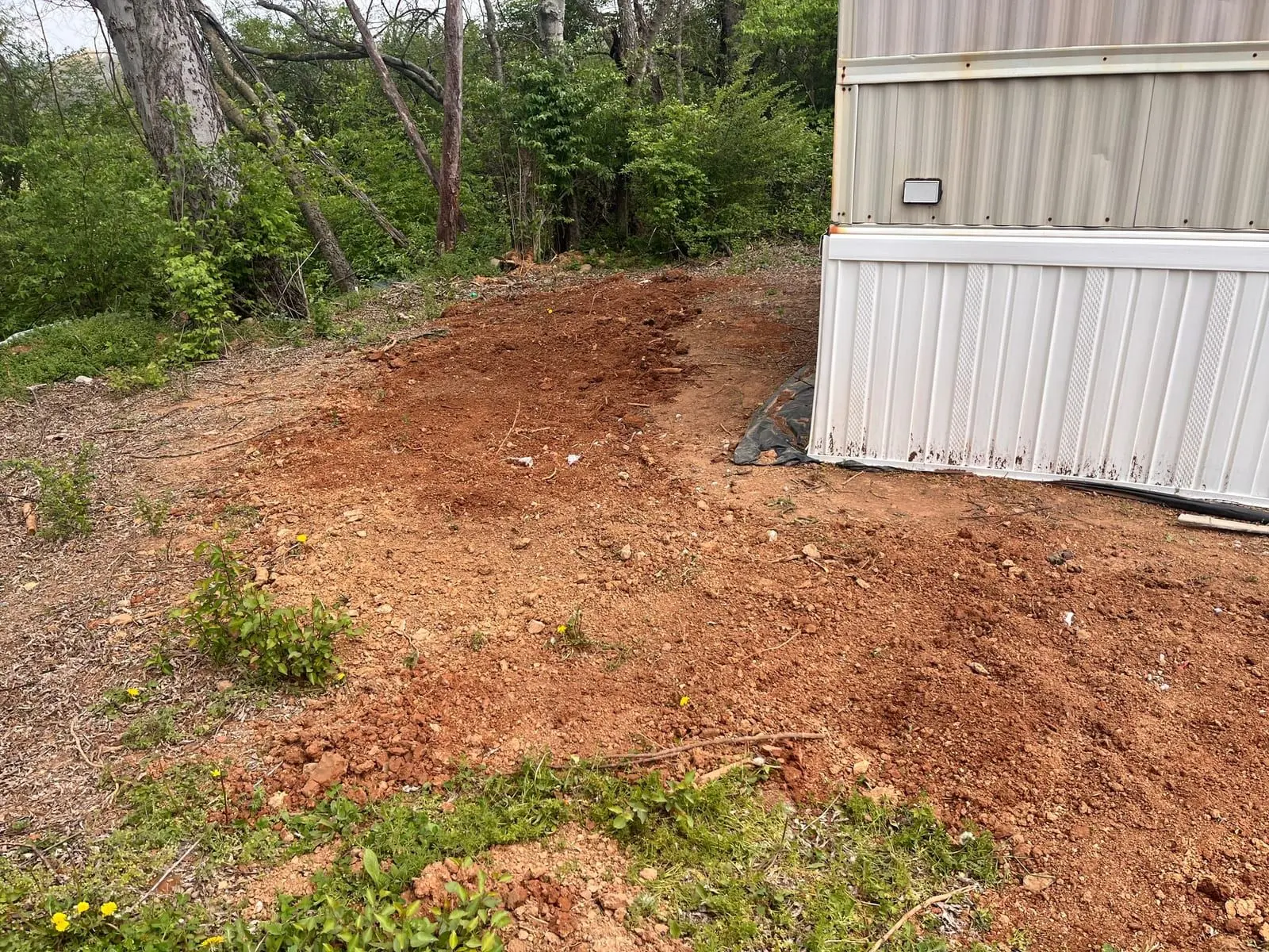 Trench and regraded run dug alongside a home for a French drain install