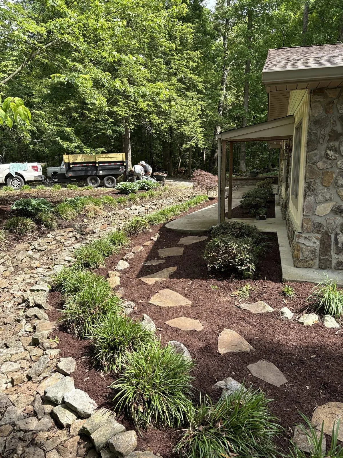 New flagstone path along a stone-foundation home with fresh plantings